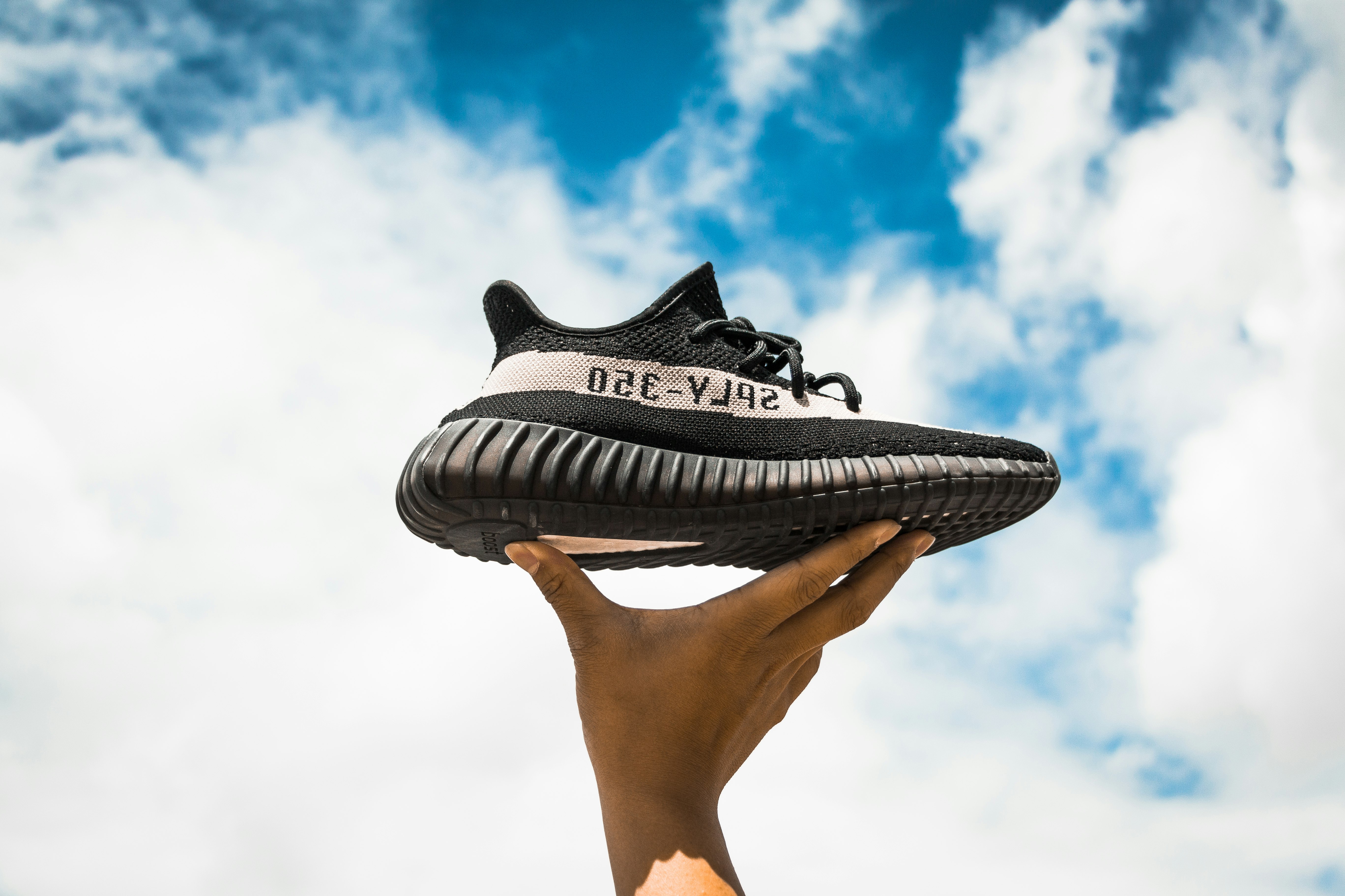 unpaired adidas Yeezy Boost 350 V2 shoe on person's hand